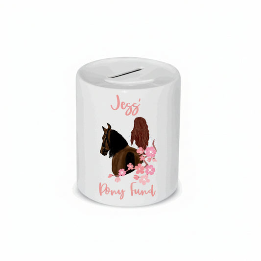 A white ceramic money box with a personalized pony fund text, an illustration of a pony, and pink floral elements.
